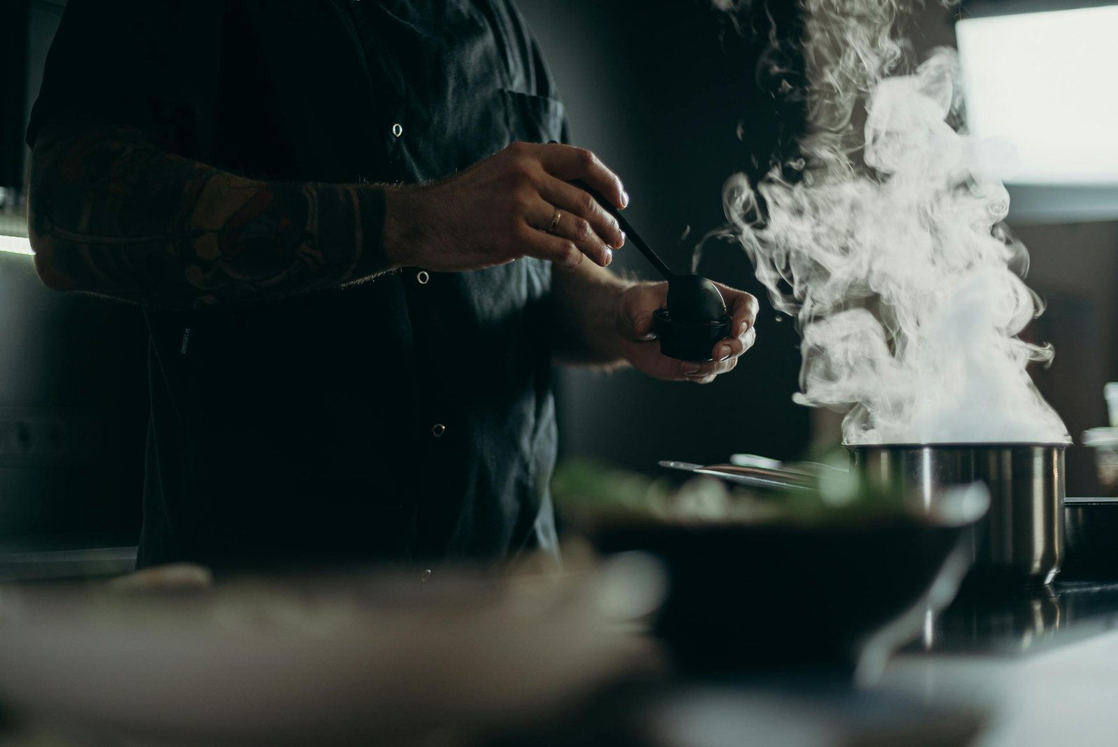 A chef carefully prepares a steamy dish in a professional kitchen setting.