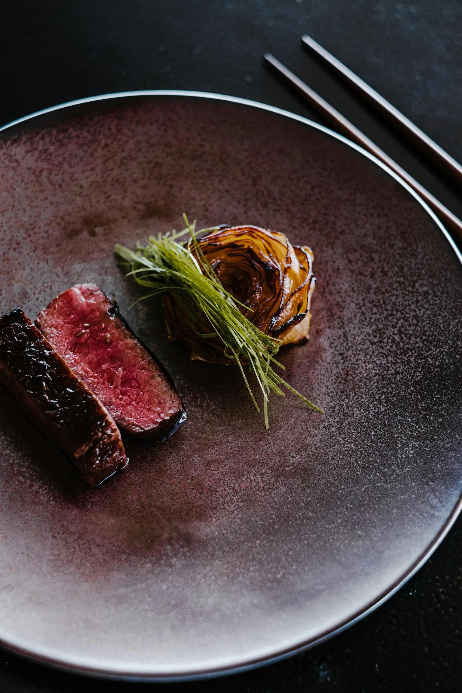 A close-up of a gourmet beef plate with grilled vegetable garnish, perfect for fine dining concepts.